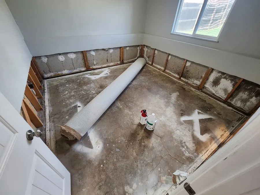 A room with flood-cut walls and the carpet rolled up after water damage in Pueblo, CO
