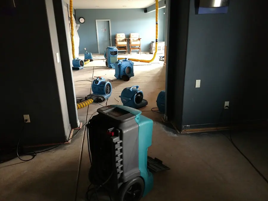 A dehumidifier and air movers drying a dark-walled room with the carpet pulled in Florence, CO