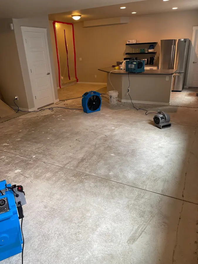 Air movers drying an open kitchen and living area in a Fountain home with the flooring pulled.
