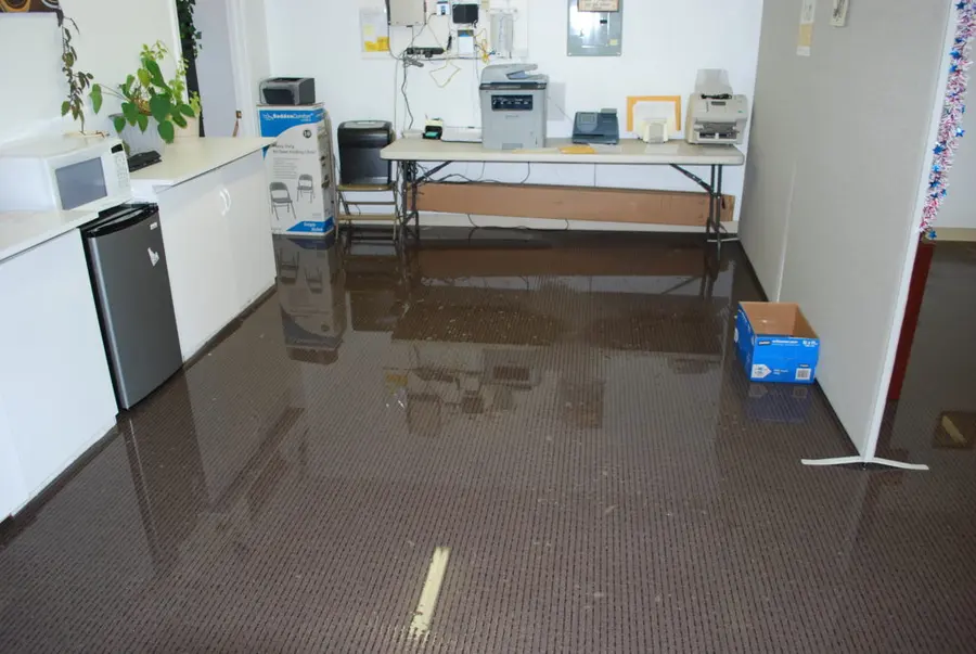 Standing water across the carpet tile of an office break room during commercial water damage in Pueblo, CO