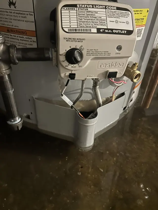 Water pooled around the base of a gas water heater after a tank leak in Pueblo, CO